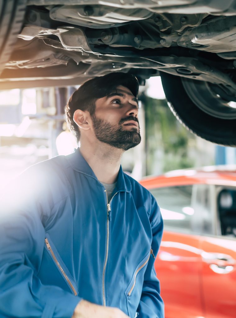 Auto mechanic looking up underneath a vehicle during its MOT test - MOT & Servicing in Allenton, Derby