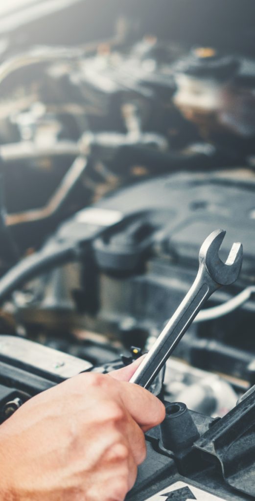 Mechanic holding a spanner looking over a vehicle engine - Car Repairs in Allenton, Derby